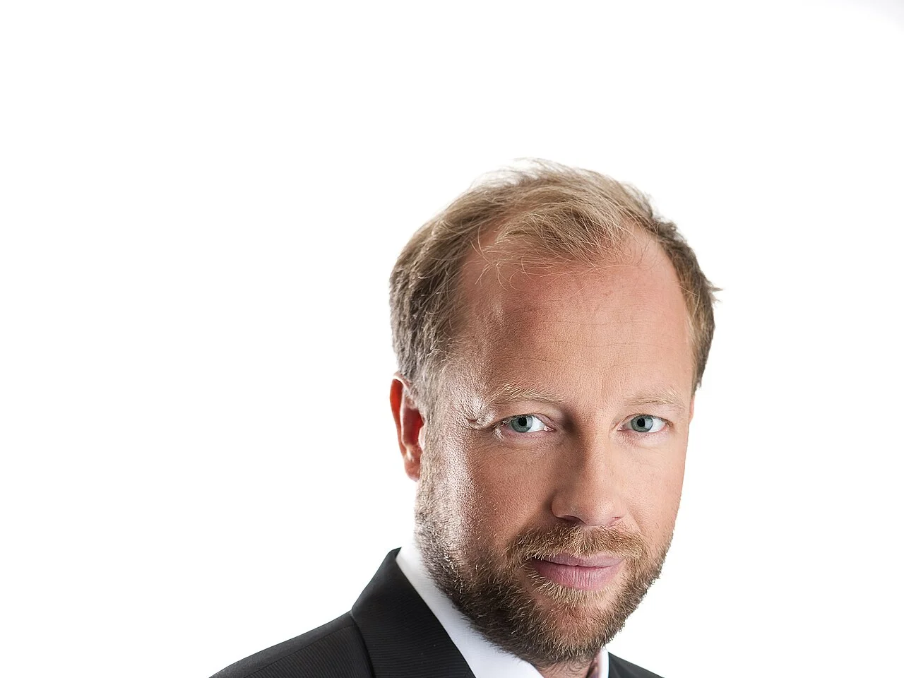 Porträtt av Petter Rönnqvist i mörk kavaj mot vit bakgrund