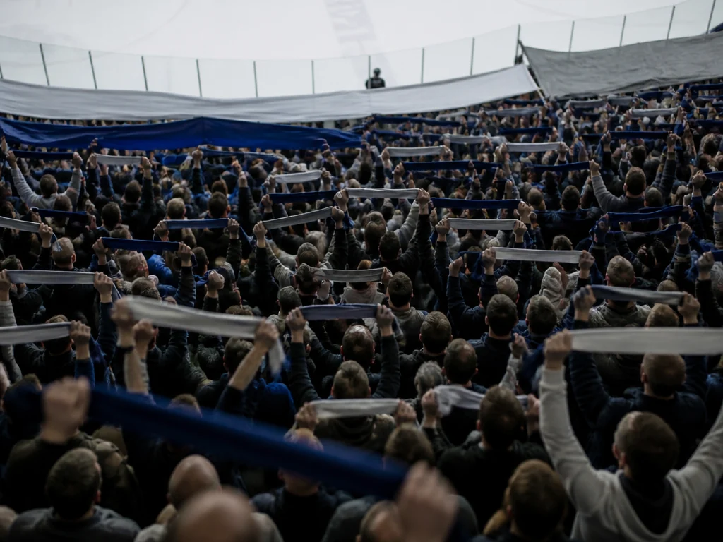 Ståplatsläktare fylld av supportrar med tifomaterial före en hockeymatch